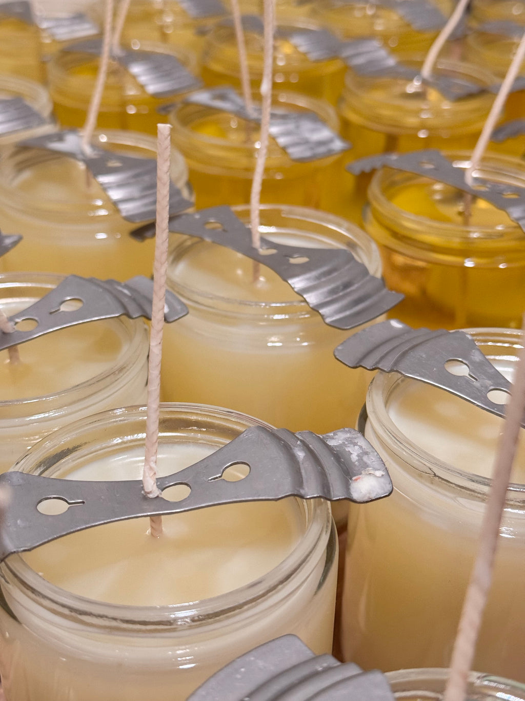 many jars of candles are lined up on a table